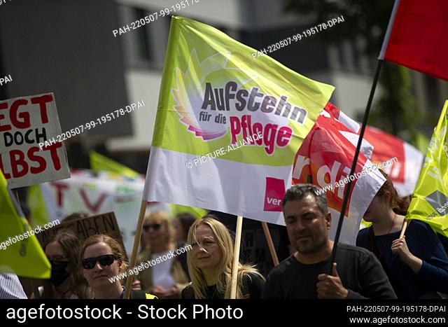 07 May 2022, North Rhine-Westphalia, Duesseldorf: A demonstrator carries a flag with the inscription ""Aufstehn für die Pflege""
