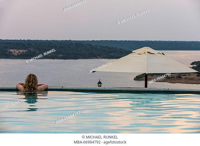 Woman relaxing in a pool above Kazinga channel in the Queen Elizabeth National Park, Uganda