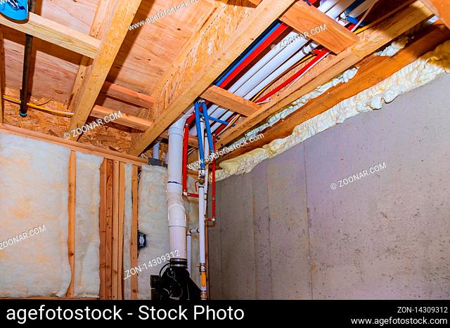 New home under construction interior PVC pipes plumbing inside a home framing with basement view