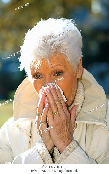older woman in autumn, having a cold