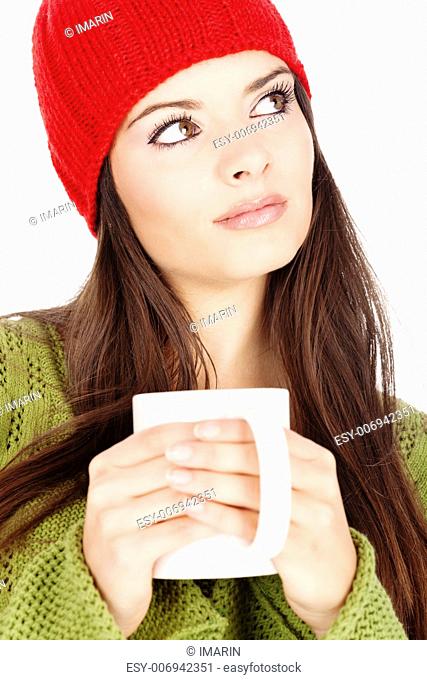 young brunette woman in wool sweater and cap holding a teapot, isolated on white