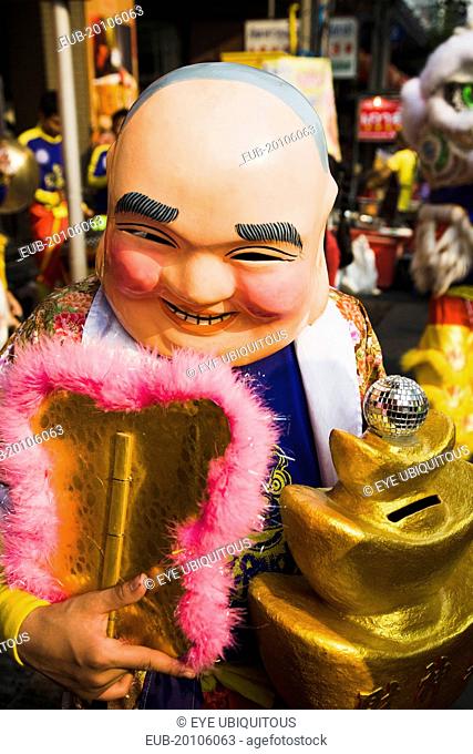 Member of dance troupe with papier mache character head and fan collecting money for Chinese New Year show