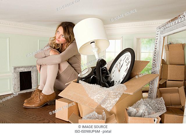Young woman with box of objects in small room