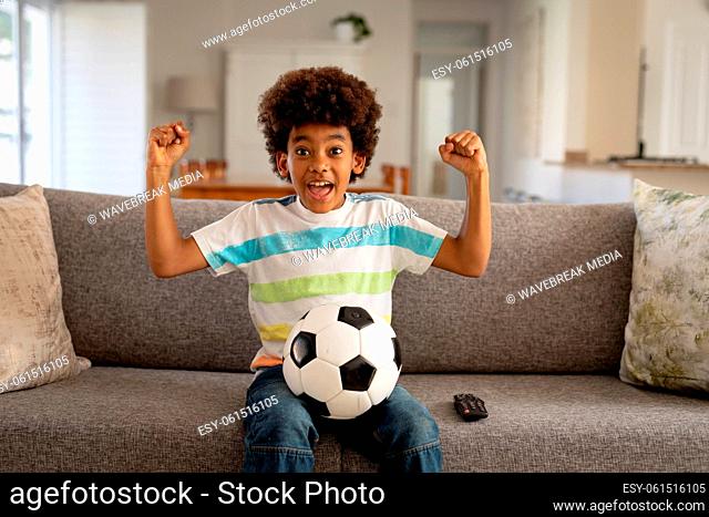 Boy with football cheering while watching sports on TV