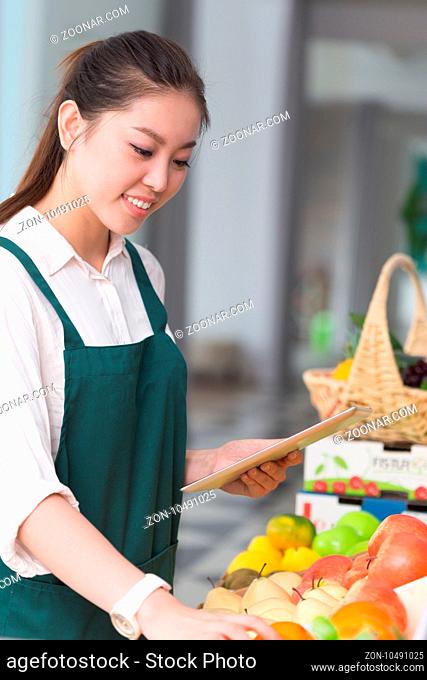 young pretty chinese woman works in fruit store