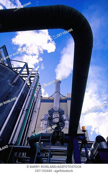 Paper industry, pulp mill, piping systems and valve, with smoking stack, against blue sky