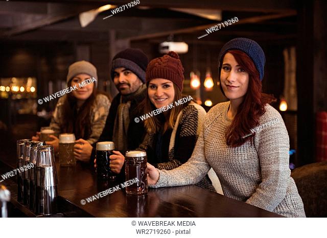 Friends holding beer glasses at bar counter