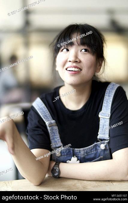Korean woman sitting at table in cafe, daydreaming