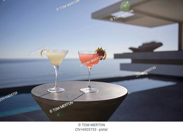 Cocktails in martini glasses on sunny luxury patio with sunny ocean view