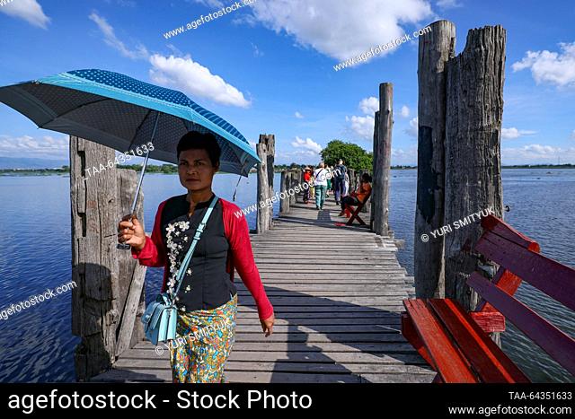 MYANMAR, MANDALAY - OCTOBER 25, 2023: A woman is seen on the U Bein Bridge spanning Lake Taungthaman. The 1.2-kilometre bridge is believed to be the world's...