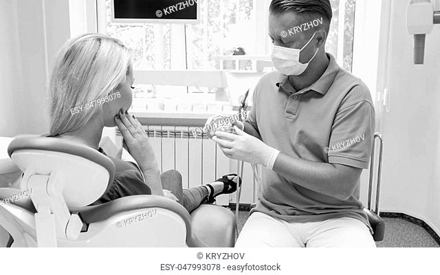 Monochrome portrait of male dentist talking to his patient before treatment