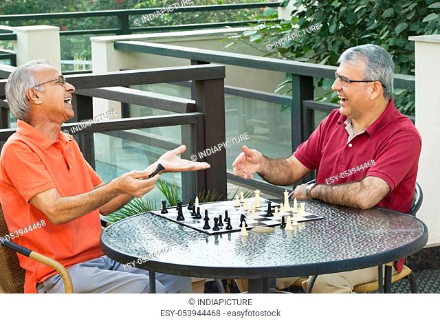 Senior men laughing while playing chess