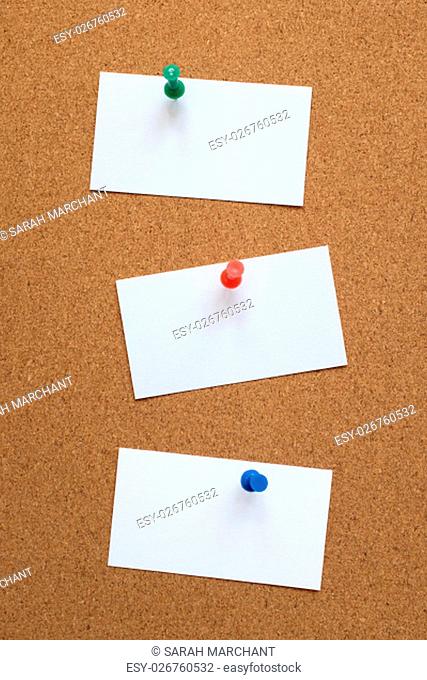 Three blank business cards pinned to a cork pin board