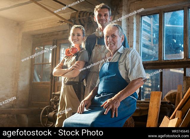 Generations of carpenters in their family business workshop looking at the camera