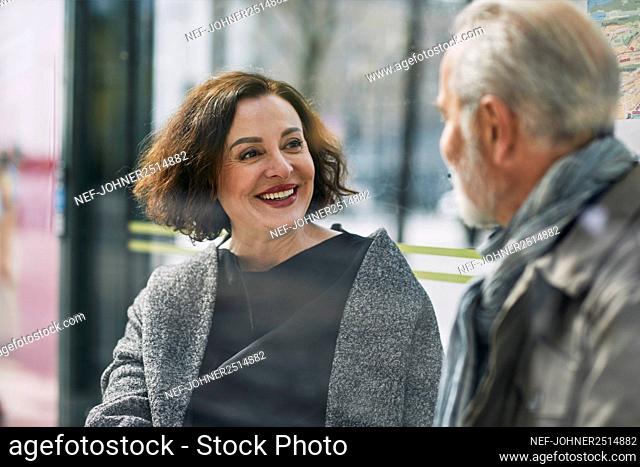 Smiling woman talking to man at bus stop