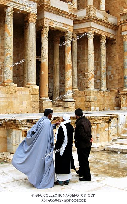 Three Arab men in traditional costumes discussing in the theatre of Sabratha, UNESCO World Heritage site Sabratha, Libya