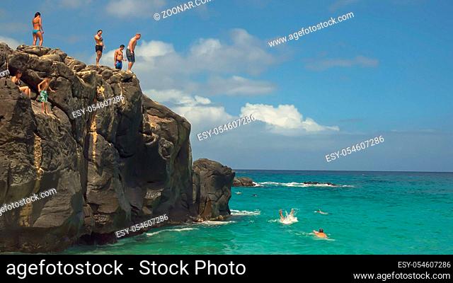 a thrill seeker dives off the large rock at wiamea bay, hawaii