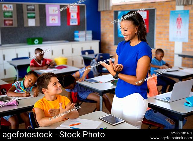 African american female teacher and caucasian boy talking in hand sign language at elementary school