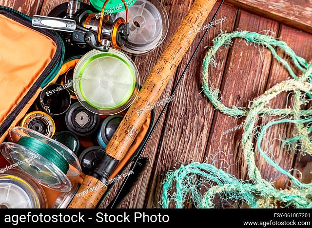 Different fishing tacles with rod and reels on wooden brown background. Mockap for advertisment and publishing
