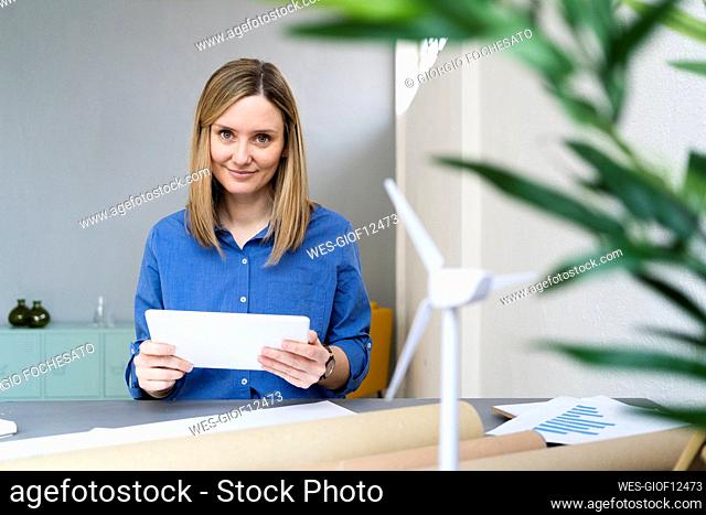 Smiling businesswoman with digital tablet at desk in studio