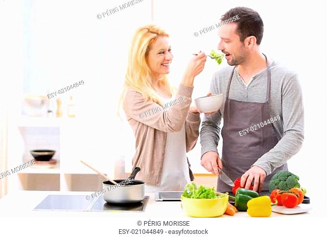 Young attractive woman give food to her husband to taste