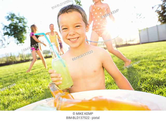 Caucasian boy drinking soda in backyard