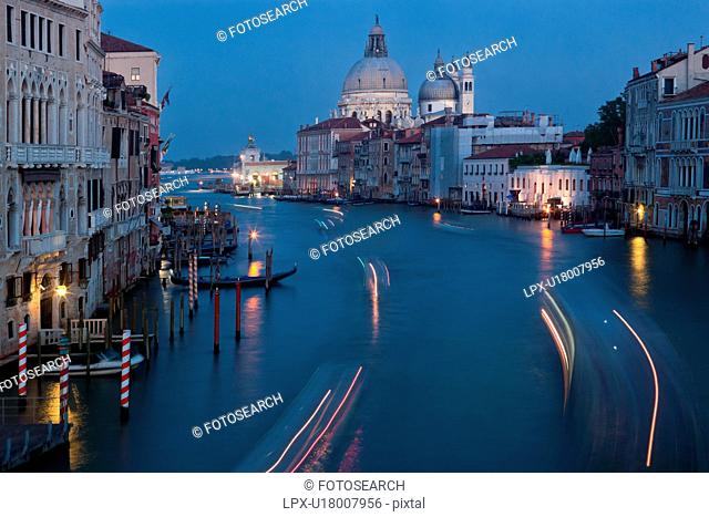 Aerial view of Grand Canal, looking towards church of Santa Maria della Salute, multicoloured lines from motion blur of boat lights at twilight
