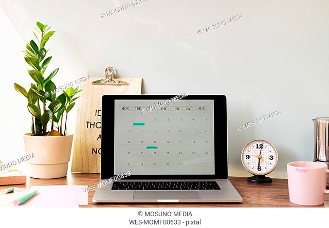 Opened laptop with a calendar on desk at home office