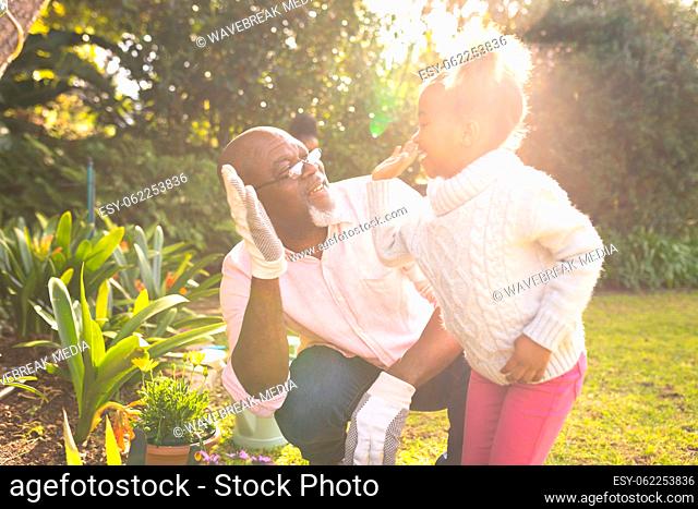 African american father and daughter spending time together in the garden and gardening