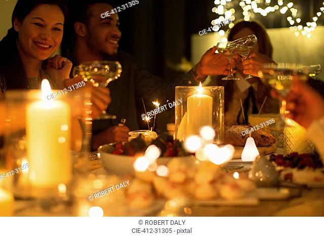 Friends toasting champagne glasses at candlelight Christmas table