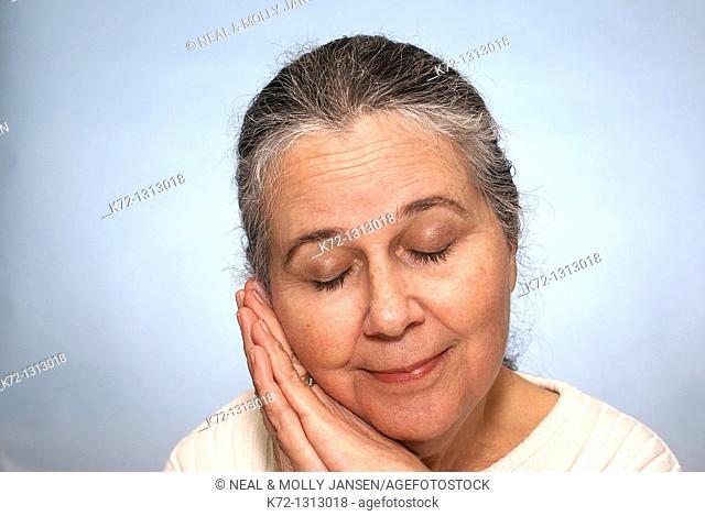 Portrait of an older woman smiling and resting with eyes closed