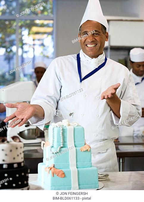 Mixed Race male pastry chef next to cake