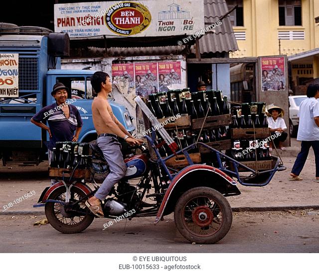 Man riding motorbike laden with beer bottles. Advertising posters
