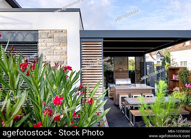 Modern covered terrace with outdoor kitchen, seating area and fireplace with Orleander and jewelry basket