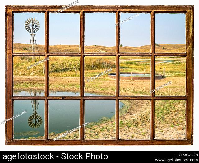 cattle drinking hole in a prairie of Nebraska Sandhills - fall morning scenery as seen from a vintage sash window