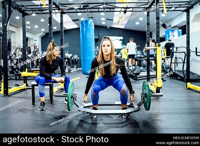 Woman exercising in gym with twin sister having a break