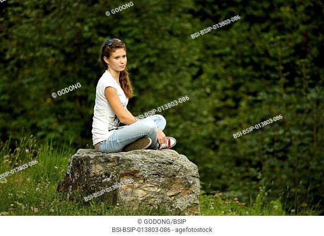 Young girl siting on a stone