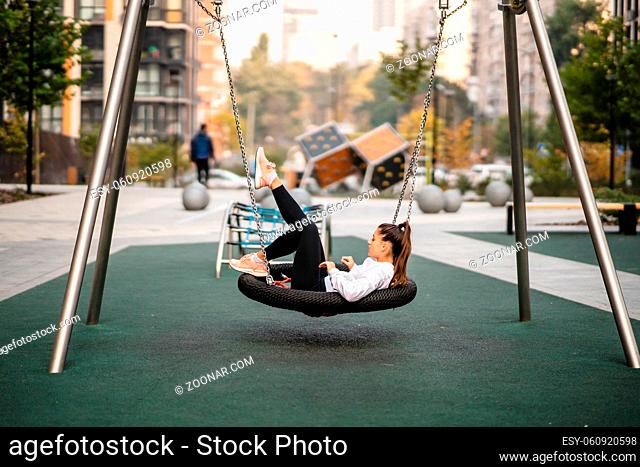 Young woman rides on a swing. Girl resting on the playground