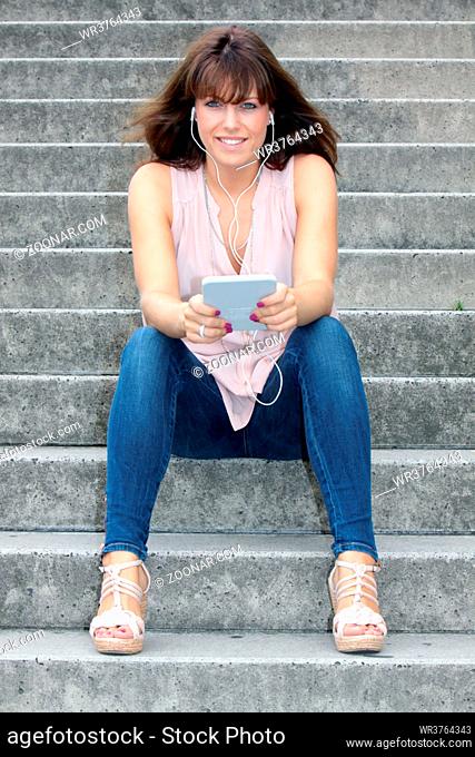 jungen Frau sitzt auf einer Treppe und liest im e-reader, Köln, Nordrhein-Westfalen, Deutschland