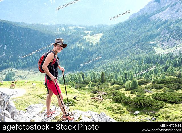 Smiling woman standing on rock while hiking on mountain