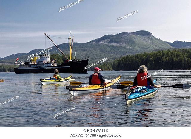 Three kayakers await pickup by the supply ship the Uchuck 111 at Flynn's Cove, Nootka Island, British Columbia, Canada. Model Released