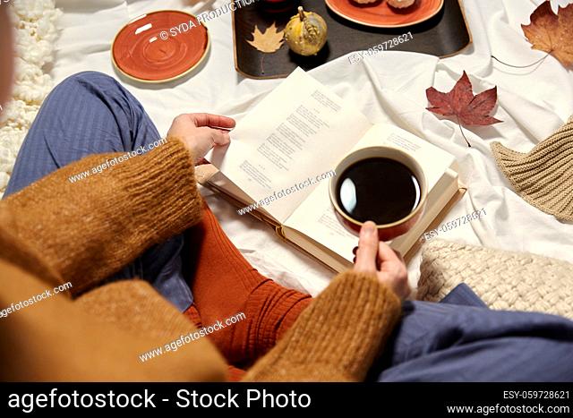 woman drinking coffee and reading book in autumn