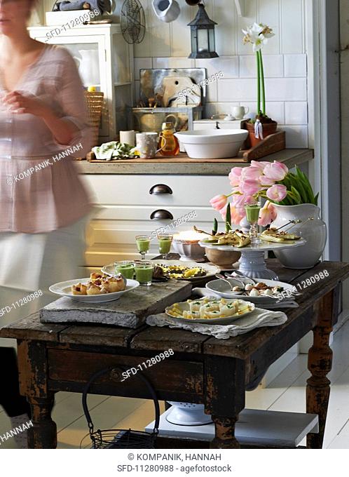 A festive buffet with various canapés on a rustic wooden table in a cosy country house-style kitchen