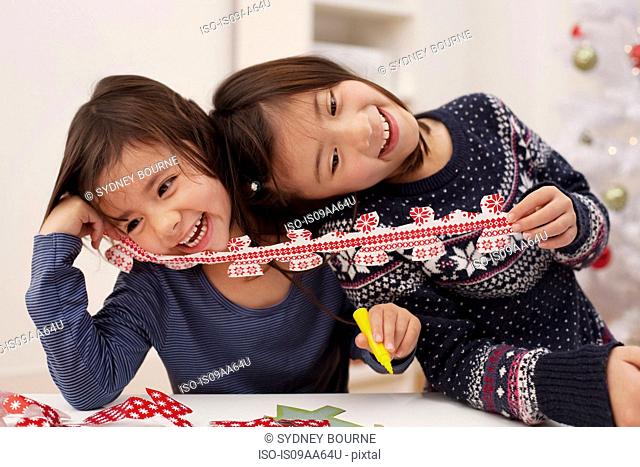 Girls holding Christmas decorations, laughing