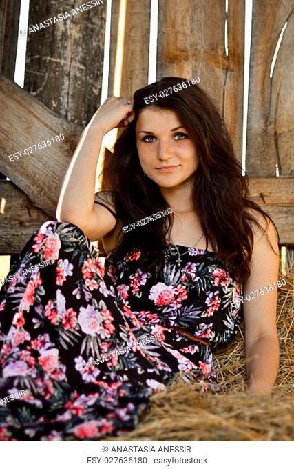 Beautiful girl sitting in the hay.Attractive girl with hay.Gorgeous woman, girl in the wooden stable, stable, yellow, dry stack of hay, haystack
