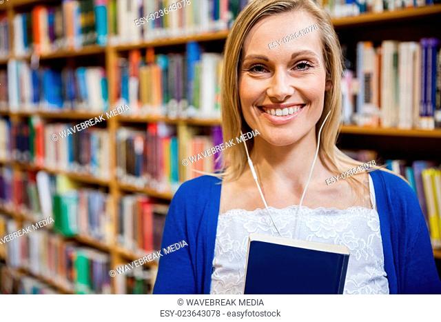 Smiling female student listening to music in the library