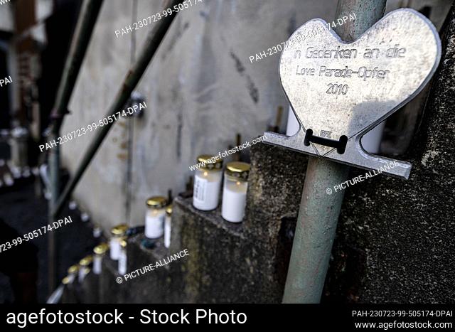 23 July 2023, North Rhine-Westphalia, Duisburg: A plaque in the shape of a heart and the inscription ""in memory of the Love Parade victims 2010"" hangs on the...