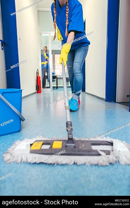 Close-up of cleaners moping the floor of a hall