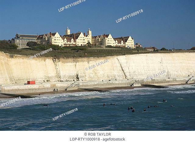 England, City of Brighton and Hove, Brighton, Surfers in the sea beneath white chalk cliffs near Brighton Marina