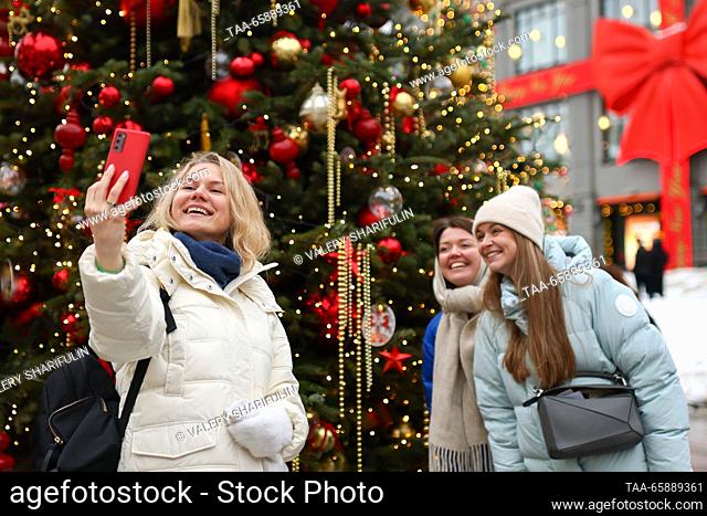 RUSSIA, MOSCOW - DECEMBER 19, 2023: Women pose for a selfie during the opening of an exhibition of designer Christmas trees in Kuznetsky Most Street